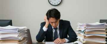 Worker overwhelmed by paperwork, clock ticking slowly.